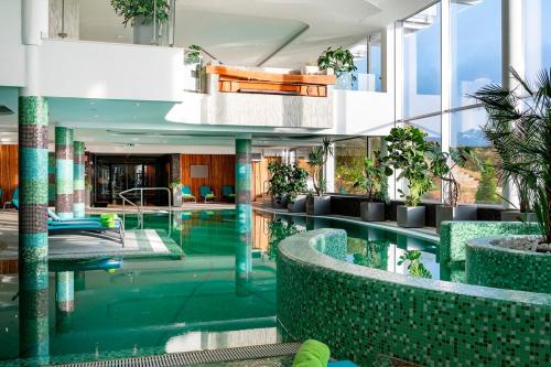 an indoor pool in a building with plants at Hotel Ózon & Luxury Villas in Mátraháza