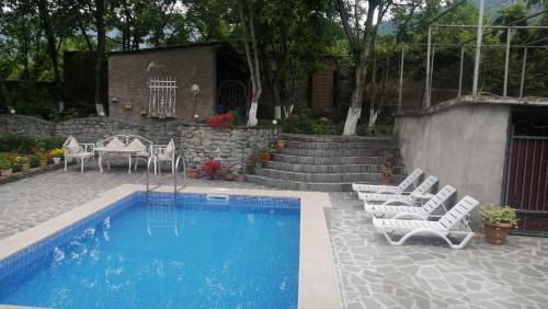 a swimming pool with white chairs and a table and stairs at Family Hotel Lago & Wine Cellar in Lagodekhi