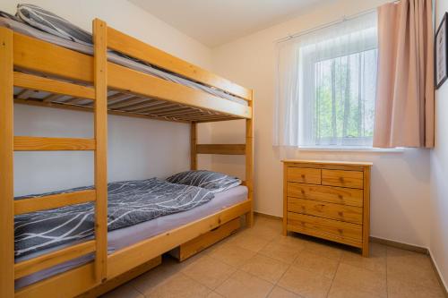 a bedroom with bunk beds and a dresser and a window at Apartmány Nad rybníky in Horní Planá