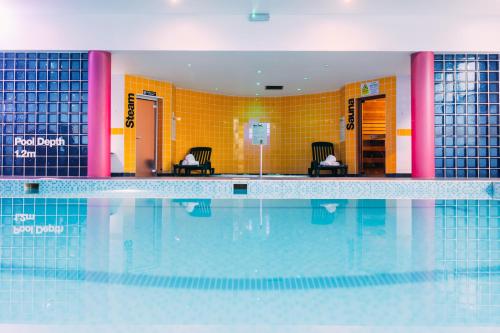 a swimming pool with two chairs in a building at Armagh City Hotel in Armagh