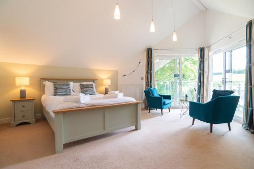 a bedroom with a bed and chairs and a large window at Trewhiddle Retreat V25 by Together Travel - Luxury 4-Bedroom Villa in St Austell
