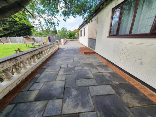 a stone walkway next to a building with a window at Bungalow in leafy area in Upminster