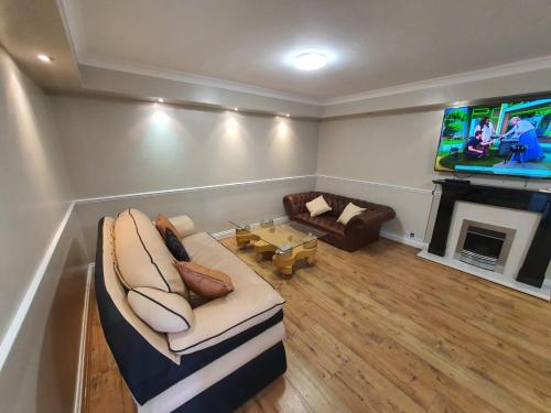 a living room with a couch and a flat screen tv at Bungalow in leafy area in Upminster