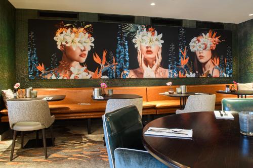 a restaurant with tables and chairs and paintings on the wall at Van der Valk Hotel Breda in Breda