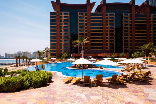 una piscina con sedie e ombrelloni di fronte a un hotel di Tiara Beach Residences, Palm Jumeirah Dubai - Mint Stay a Dubai