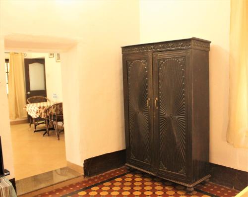 a black cabinet in the corner of a room with a table at Granpa's Inn Hotel Bougainvillea in Anjuna