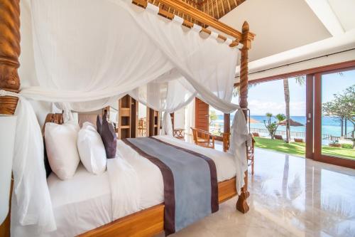 a bedroom with a canopy bed with a view of the ocean at Villa Dahlia, 4 bed Oceanfront Retreat, Candidasa in Manggis