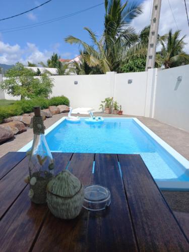 a pool with a wooden table next to a swimming pool at Bois Mapou Self Catering Apartments Unit 103 in Rivière Noire