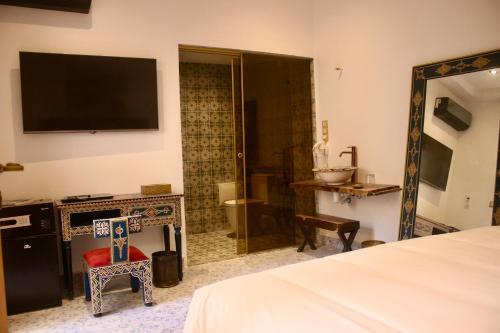 1 dormitorio con cama, espejo y TV en Riad Mellah, en Essaouira