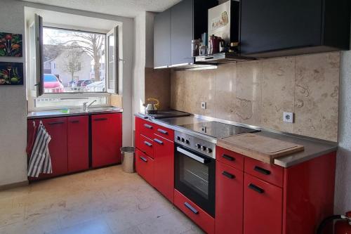 uma cozinha com armários vermelhos e um forno de fogão vermelho em Stylish large 4 room apartment close to the center em Grenzach-Wyhlen