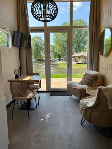 a living room with a table and chairs and a large window at Tiny House in Kesteren