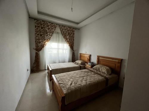 a bedroom with two beds and a window at Cozy Apartment with Pool near Beach in Mohammedia