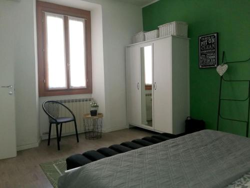 um quarto com uma cama, uma cadeira e uma parede verde em Appartamento Verde em Como