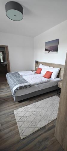 a bedroom with a bed with white sheets and red pillows at Penzion Königův mlýn in Loučná pod Klínovcem