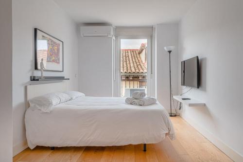 Habitación blanca con cama y ventana en Studio La Latina by SharingCo, en Madrid