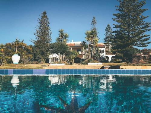 a swimming pool in front of a house with trees at Quinta de Lagos in Lagos