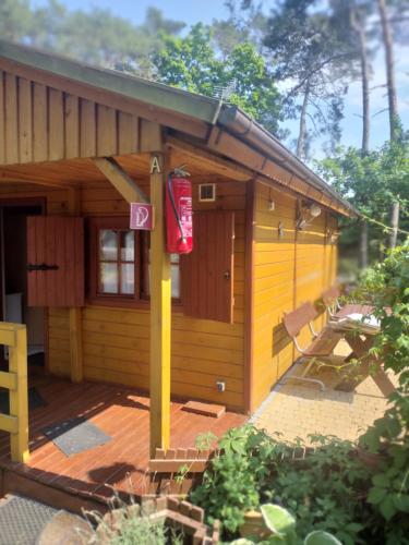 mały żółty dom z gankiem i znakiem w obiekcie Domek MONA-3pokojowy z tarasem- przy morzu w mieście Krynica Morska