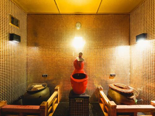 a tiled bathroom with two toilets and an orange tub at Arima Kirari in Kobe