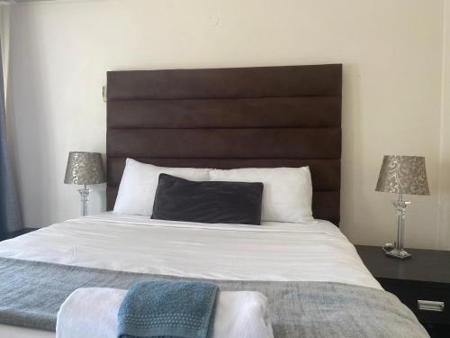 a bedroom with a large white bed with two lamps at Safari Apartments -Beautiful 3 bedrooms, 10-seater dining , TV room, Garden & Pool in Johannesburg