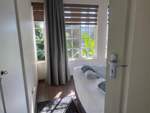 a bedroom with a bed and a window at Safari Apartments -Beautiful 3 bedrooms, 10-seater dining , TV room, Garden & Pool in Johannesburg