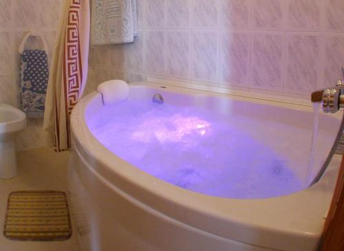 a bath tub filled with blue water in a bathroom at CASASBLANCAS. Casa nr 6 in Mecina Bombarón