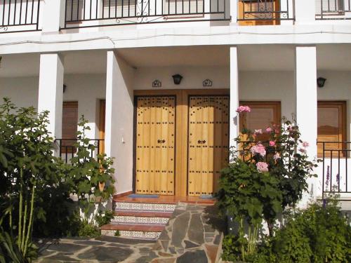 una casa con puertas de madera y flores delante de ella en CASASBLANCAS. Casa nr 6 en Mecina Bombarón