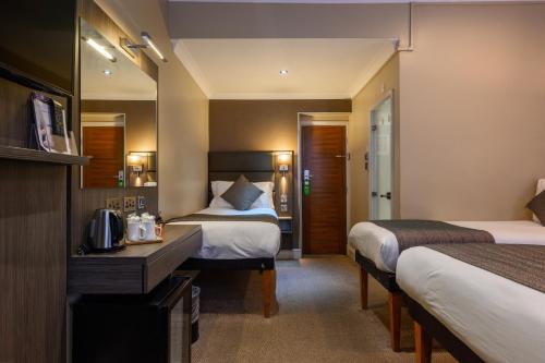 a hotel room with two beds and a desk at Brunel Hotel in London