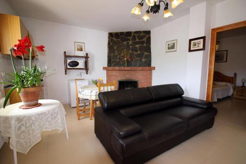 a living room with a leather couch and a fireplace at CASASBLANCAS. Casa nr 6 in Mecina Bombarón