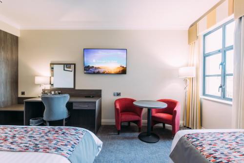 a hotel room with two beds and a table and chairs at Armagh City Hotel in Armagh