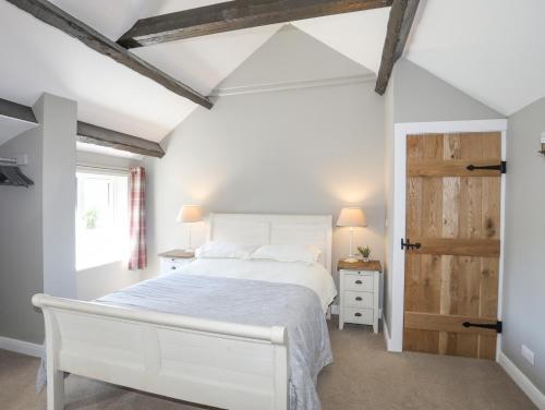 a bedroom with a white bed and a wooden door at The Keepers Lodge in Pwllheli