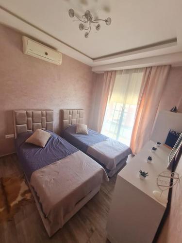 1 dormitorio con 2 camas, mesa y ventana en Appartement paisible Haut FOUNTY, en Agadir