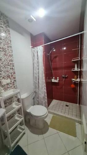 y baño con aseo y ducha de color rojo. en Appartement paisible Haut FOUNTY, en Agadir