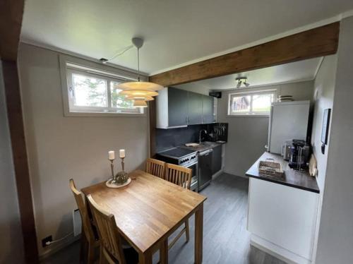 Koselig leilighet i hytteområde på Gautefall في Drangedal: مطبخ مع طاولة خشبية وغرفة طعام