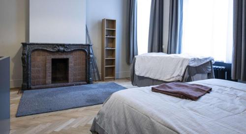een woonkamer met een open haard en 2 bedden bij Chic 3-bedroom apartment for rent to professionals in Ixelles in Brussel