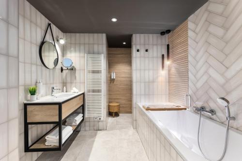 een badkamer met een bad, een wastafel en een spiegel bij Suites Boulevard 17 in Vlissingen