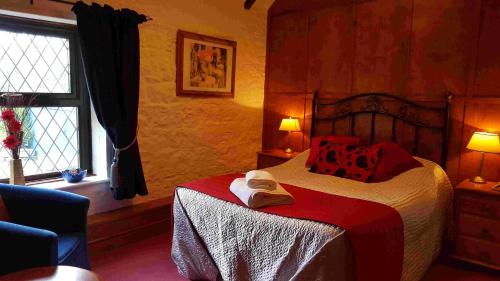 Un dormitorio con una cama con almohadas rojas y una ventana en The Walnut Tree en Yeovil