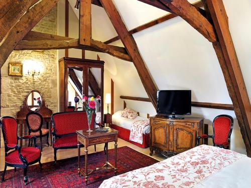 - une chambre avec un lit et une table avec une télévision dans l'établissement Hôtel Le Manoir De Mathan Crépon à la campagne 5 mn d'Arromanches et 10 mn de Bayeux, à Crépon