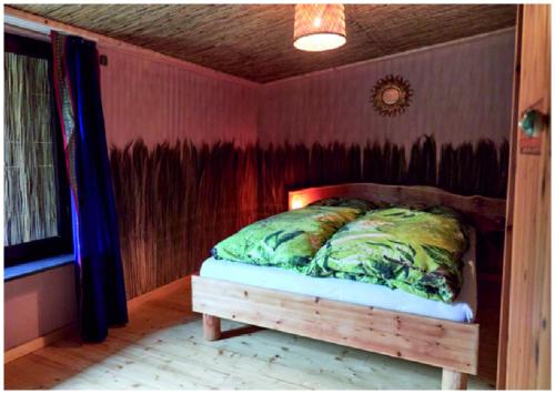 uma cama num quarto com uma parede vermelha em Elfenhütte Ferienhaus Eifel em Rott