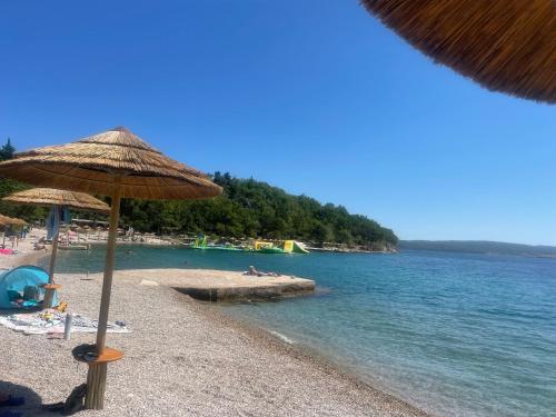a beach with an umbrella and people on the water at Lux dodo in Dramalj