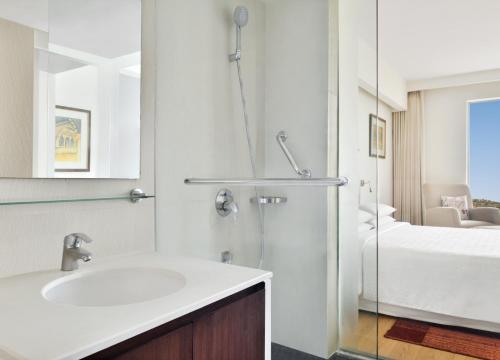 a bathroom with a sink and a shower and a bed at Four Points by Sheraton Jaipur, City Square in Jaipur