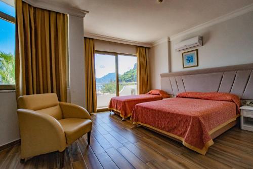 ein Hotelzimmer mit 2 Betten, einem Stuhl und einem Fenster in der Unterkunft MARBAS SELECT BEACH , Adult Only 14 Plus in Marmaris