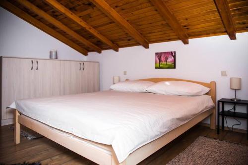 a bedroom with a white bed with a wooden ceiling at Holiday home Anica in Čavoglave