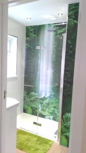 La salle de bains est pourvue d'une douche et d'un tapis vert. dans l'établissement London luxury en-suite double room, private door, park free, tram, tube!, à Mitcham