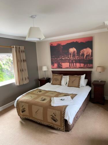 a bedroom with a large bed with a painting on the wall at Arrandale Lodge in Norwich