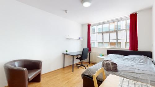 a bedroom with a bed and a desk and a chair at Superb Studio Apartment in London