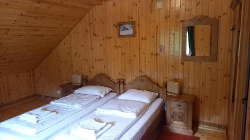 - 2 lits dans une chambre dotée de murs en bois dans l'établissement Pensiunea agroturistică Casa Brădeana, à Albac