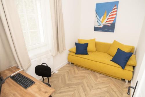 a yellow couch with blue pillows in a room at Villa GreenTree - with Private Pool, close to Budapest in Budakalász