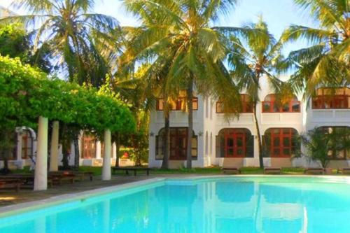 ディアニ・ビーチにあるApartment, pool, beach access nearby C221のヤシの木が茂る建物の前にあるスイミングプール