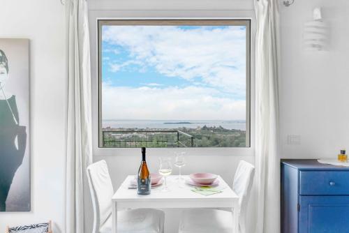 a white table and chairs with a large window at [Piscina Panoramica] - La Casa Volante in Soiano del Lago