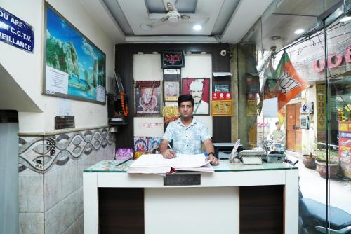 a man sitting at a desk in a room at Hotel Ashirwad DX in New Delhi